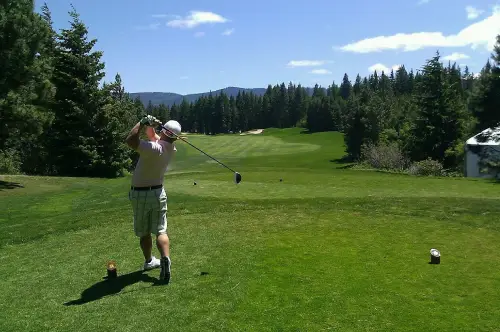 A man swinging at a golf ball on the course.