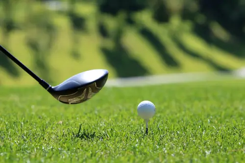 A golf ball is in the air as it hits a tee.