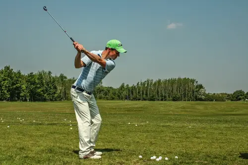 A man swinging at a golf ball on the green.